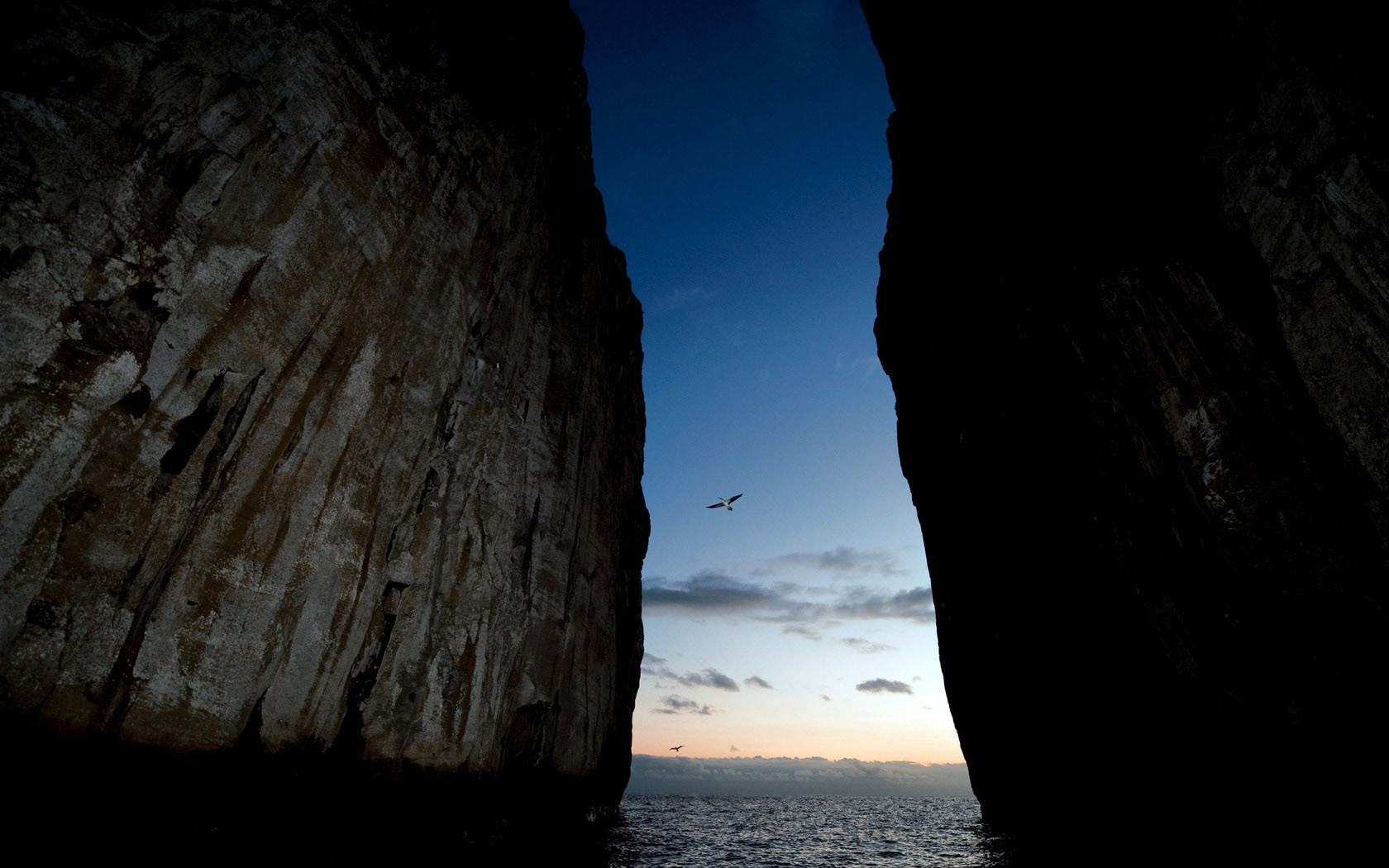 一道深邃的岩石裂隙指向远方海天相接的蔚蓝地平线，自然之力在此奏响山海交响