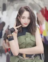 吴宣仪身穿军绿色连身短裙在舞台中央自信舞动，裙摆飞扬