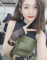 吴宣仪侧身回眸眼神灵动，舞台光影勾勒其优雅侧颜