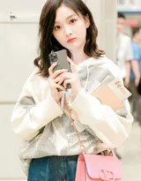 吴宣仪机场造型，宽松白色连帽卫衣搭配毛边牛仔短裤，对镜头露出甜美微笑