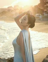 倚靠礁石小憩，裙摆如流水般铺散开来，她展露温柔浅笑，午后的阳光为整个人镀上金边，静谧而美好