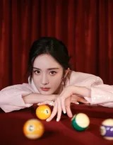 杨幂坐在台球桌沿，一手随意搭在腿上，一手轻握球杆，抬头望向远方，姿态放松而充满女王般的从容气度