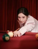 杨幂俯身准备击球，专注的目光瞄准前方，粉色的亮片身影在深色台球桌面上形成一道耀眼而优美的弧线