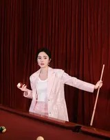 杨幂背对镜头回眸，光影勾勒出她完美的身体线条与精致侧脸，粉色西装背影在暗调中如同一幅华丽的油画