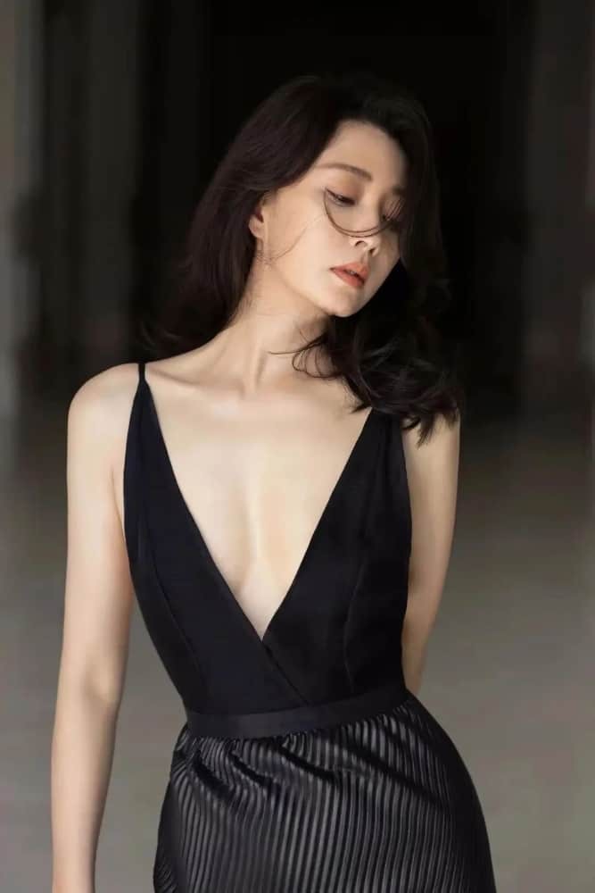 殷桃回眸浅笑，卷发慵懒垂肩，黑色裙摆随风轻扬，风情万种