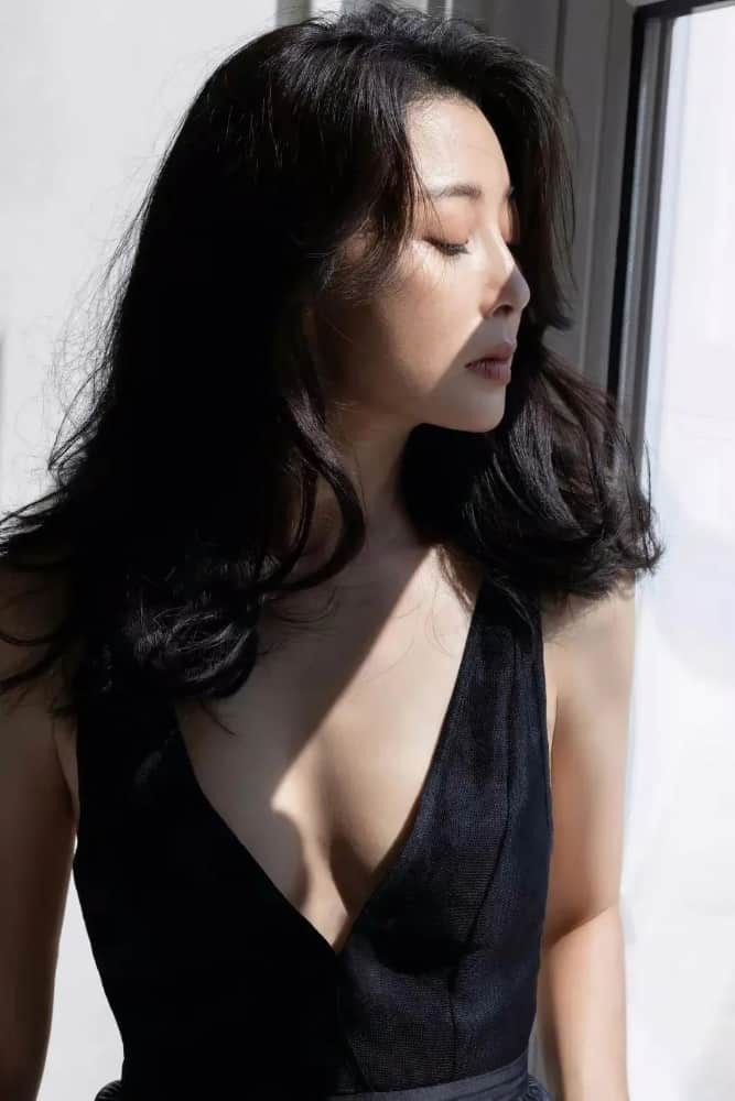 殷桃倚靠窗边，深V领口勾勒完美身段，光影交织间尽显高级质感