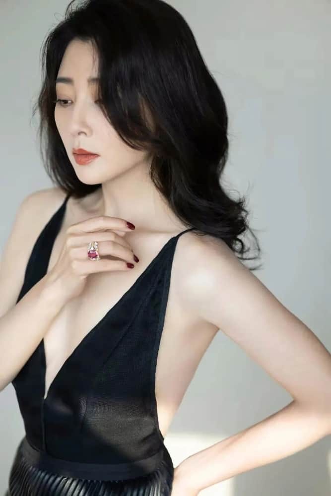 灯光下殷桃肌肤胜雪，深V黑裙与红唇形成强烈视觉冲击，冷艳迷人