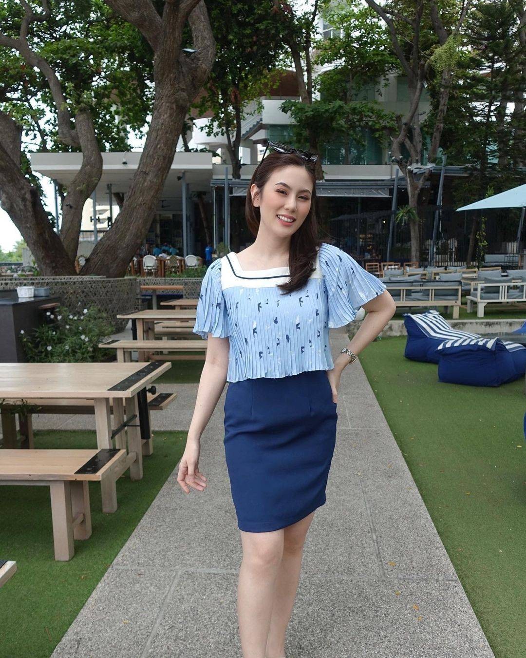 女子身着黑色皮草倚坐，烟熏眼眸微抬，指尖轻触唇瓣，危险与诱惑在无声中交织