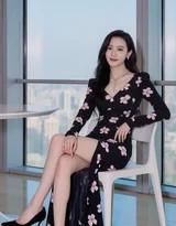 午后暖阳透过白纱帘洒入室内，少女蜷坐在窗边，黑色碎花裙摆铺散开来，她沉浸于书页或沉思中，画面温暖而安宁