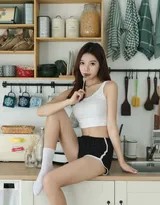 少女慵懒地坐在厨房中岛旁，一手轻托脸颊，眼神带着些许漫不经心的思索，仿佛沉浸在属于自己的世界里。