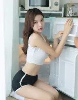 她微微俯身，黑色短裤下伸展出修长纤细的双腿，光洁的肌肤在自然光下泛起柔和光泽，姿态放松而自在。