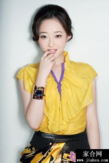 蒋梦婕身着粉色长裙于海边漫步，海风轻拂裙摆与发丝，笑容舒展而自在