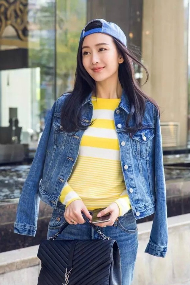 王鸥侧身回眸浅笑，牛仔装扮在都市光影下更显温柔与随性