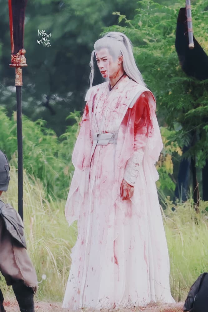 皑皑白雪中，一袭白衣的相柳静静躺卧，鲜血如红梅绽放在素白战袍上，银发与雪色交融，手中紧握的珍珠泛着微光，仿佛封存了此生最后的温柔与牵挂