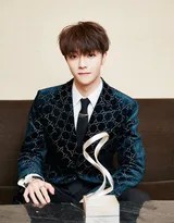 陈立农身着经典黑色西装侧身而立，柔和灯光勾勒出挺拔身姿与精致侧脸线条，眼神温润望向远方