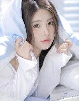 女孩置身于绿意盎然的植物旁，仰头感受阳光，牛仔短裤与自然背景融为一体，充满生机活力