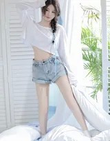 少女坐于木质地板，双手抱膝，眼神清澈望向镜头，身后是温暖的光源，整个场景安逸而美好