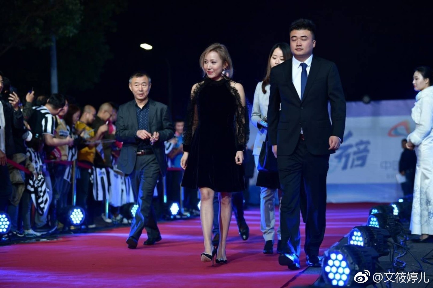 文筱婷侧身立于光影中，修身裙装勾勒曼妙曲线，微卷长发轻披肩头，眼神沉静望向远方