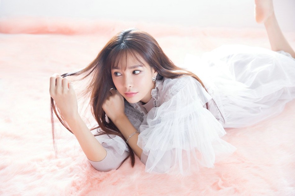 沈梦辰一袭白裙立于春色之中，侧首浅笑发丝轻扬，尽显清新柔美气质