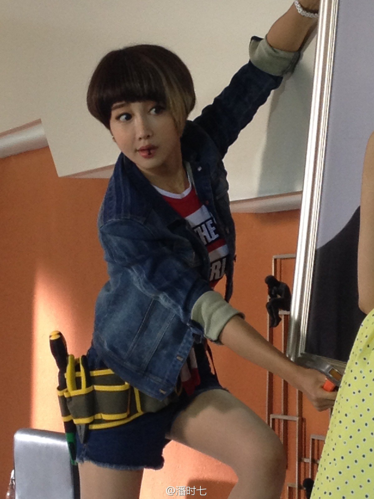 潘时七身穿浅色牛仔短裤搭配简约上衣，侧身回眸间展露优雅身姿与自信笑容