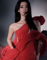 王楚然倚靠于深色背景前，红裙与环境形成强烈对比，姿态放松而富有韵味