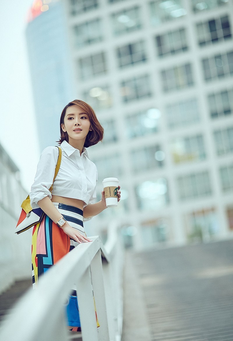 车永莉手提精致小包行走于街头，驼色套装在冬日阳光下散发柔和光泽，步履从容