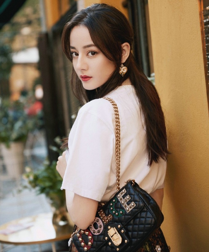 倚靠铁艺栏杆，热巴眼神温柔望向远方，毛衣纹理在特写下细腻可见