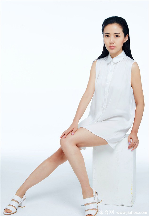 颜丹晨身着白色镂空长裙侧身凝望，眼神温柔似水，发丝轻扬间尽显静谧优雅