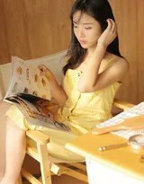 盘腿坐在沙发上的圆脸美少女，微笑着展示杂志内容，眼神灵动，充满生活情趣