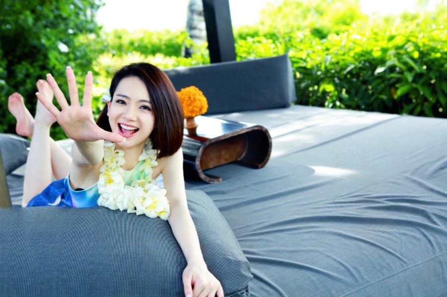 戚薇坐于沙滩上手捧清新椰青，开怀大笑尽显俏皮少女感