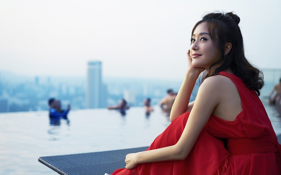 秦岚侧身立于花丛旁，黑色短靴与吊带裙碰撞出时尚火花