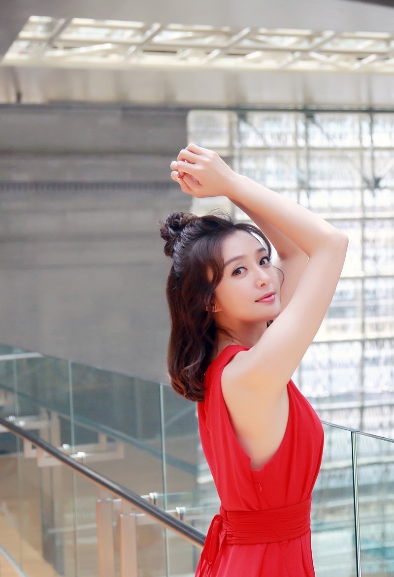 秦岚身着白色波点吊带裙在法式花园中优雅回眸，阳光洒落肩头