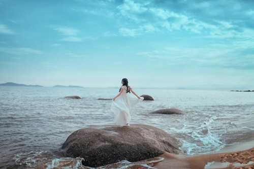 轻纱掩面女子立于枯枝前，侧影尽显落寞