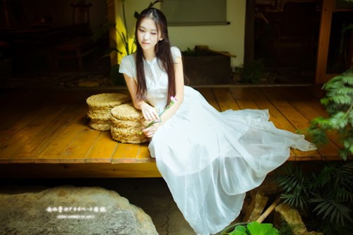 红墙窗棂前，古装女子执扇半遮面