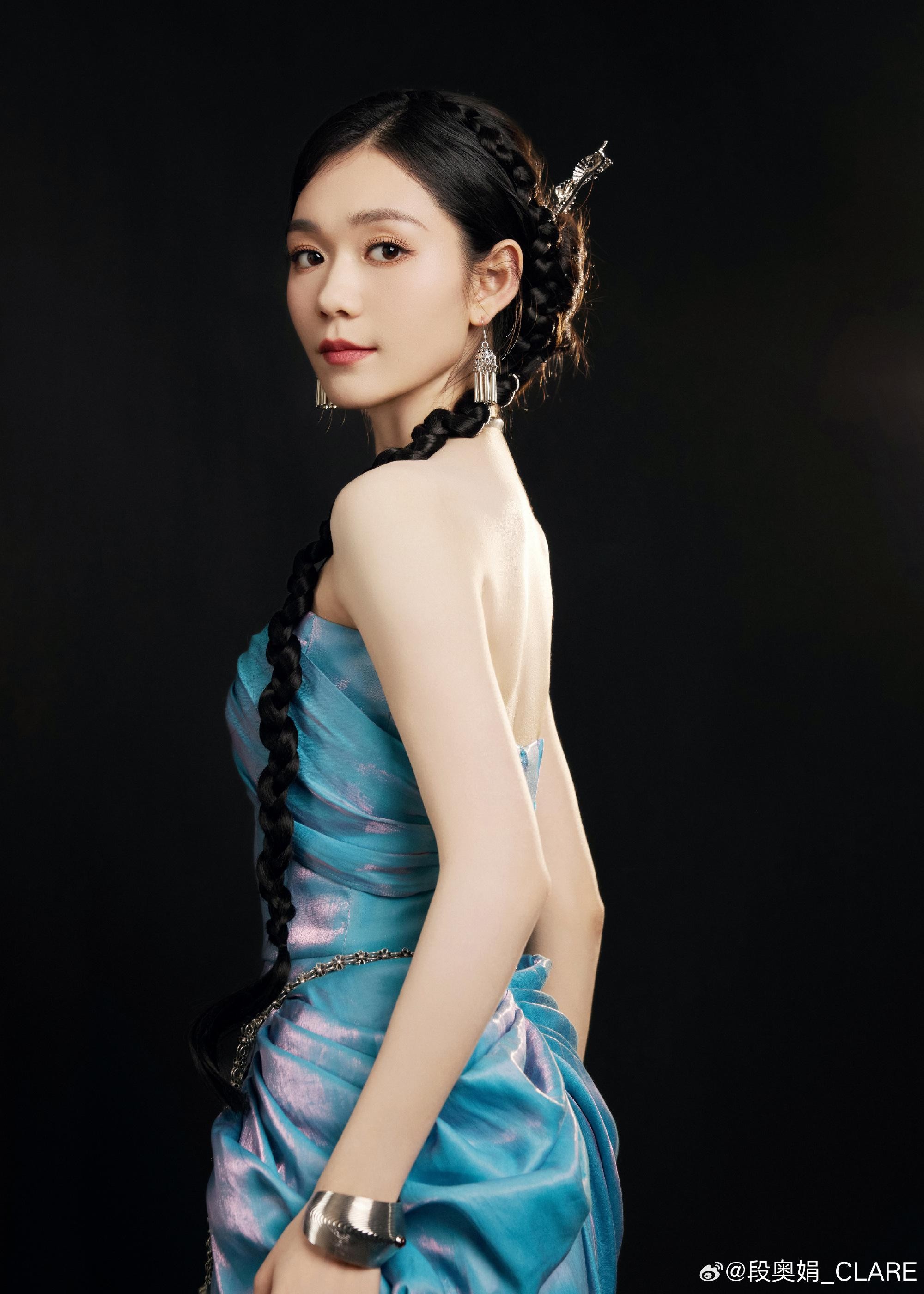 段奥娟身着浅色纱裙立于朦胧光影中，回眸瞬间眼神清澈而坚定，宛如森林中走出的精灵