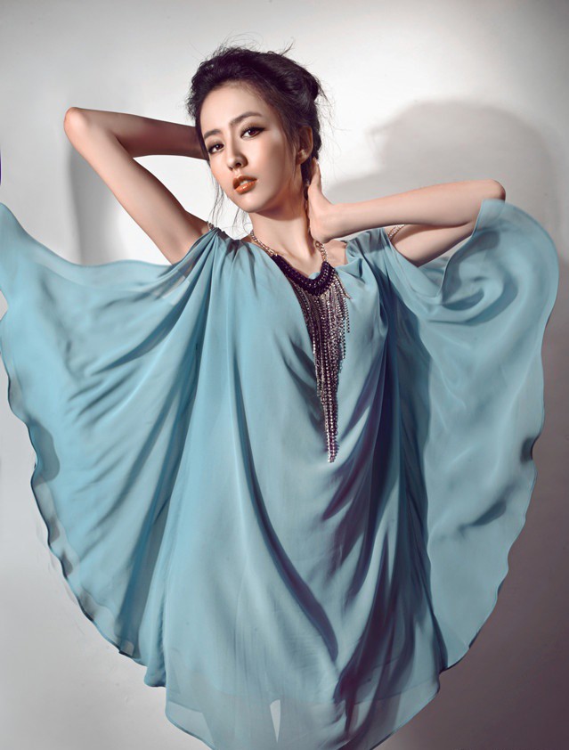佟丽娅身着纯白曳地长裙侧身回眸，眼眸深邃如星辰，耳畔流苏耳环摇曳生姿