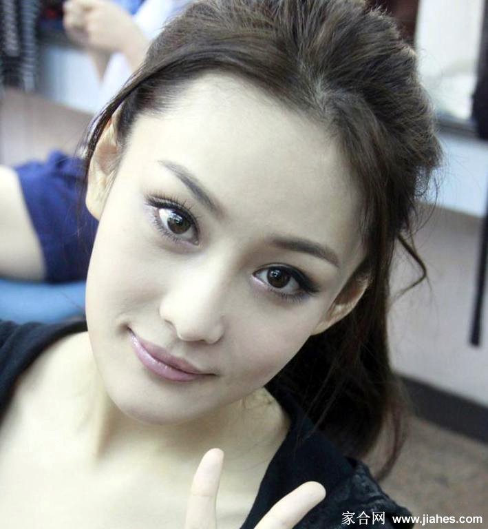 置身于光影交织的背景前，张馨予姿态舒展，优雅中透露出独立洒脱的气质