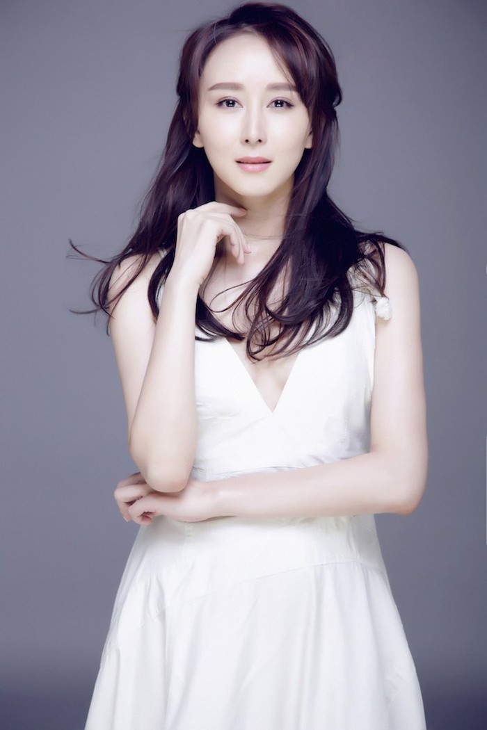 胡静手抚秀发展露明媚笑容，优雅气质与白色裙装相得益彰