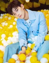 邢昭林置身于蓝色海洋球池中央，双手轻抚球面，嘴角扬起一抹轻松惬意的微笑，仿佛沉浸于无忧无虑的玩乐时光