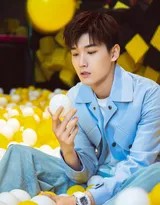 邢昭林慵懒地倚靠在海洋球池边，手持几只蓝色小球目光专注，牛仔套装与背景融为一体，尽显随性不羁的时尚态度