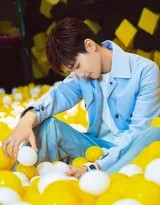 邢昭林身着浅蓝牛仔外套侧身回眸，眼神清澈而温柔，身后缤纷的海洋球如梦幻背景般铺展开来