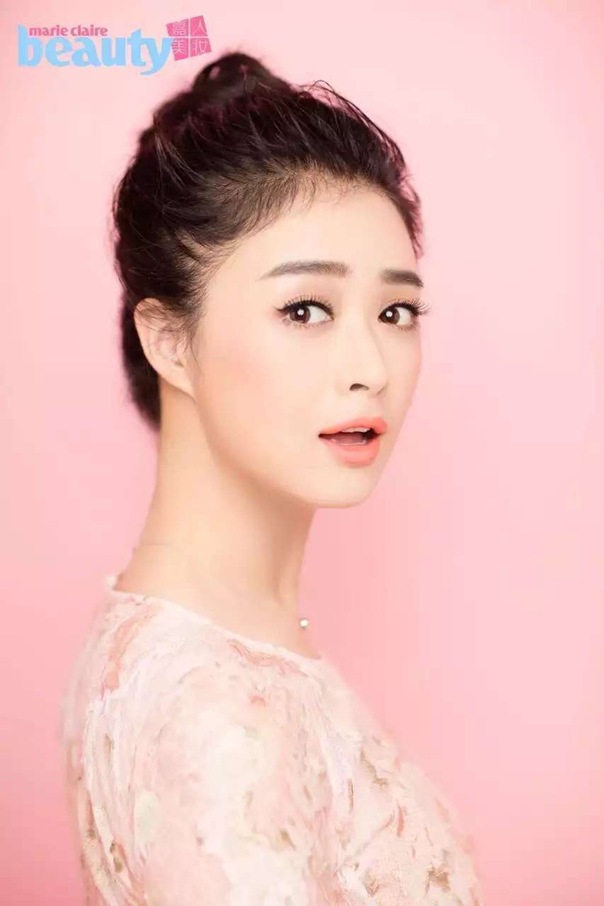 蒋欣身着旗袍优雅端坐，手持石榴浅笑，寓意吉祥，韵味十足