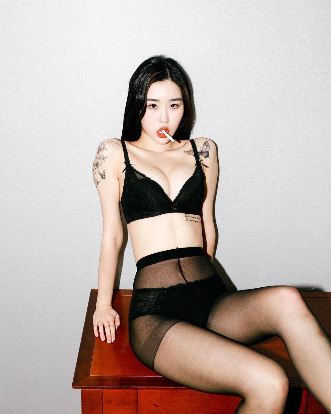 模特侧身凝视镜头，肩颈与背部的蝴蝶纹身如羽翼轻展，与黑色内衣形成鲜明对比