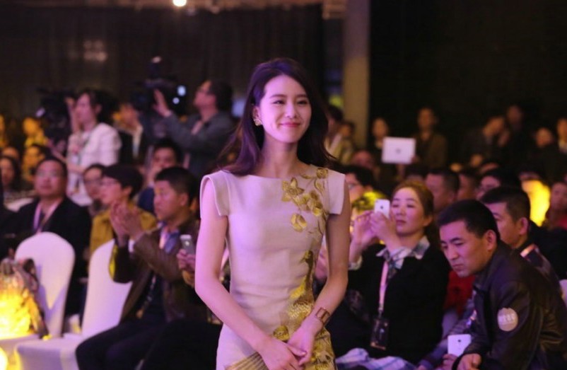 刘诗诗侧身而立，一袭素雅印花旗袍勾勒出优美身段，手持团扇回眸浅笑，尽显温婉含蓄的古典韵味