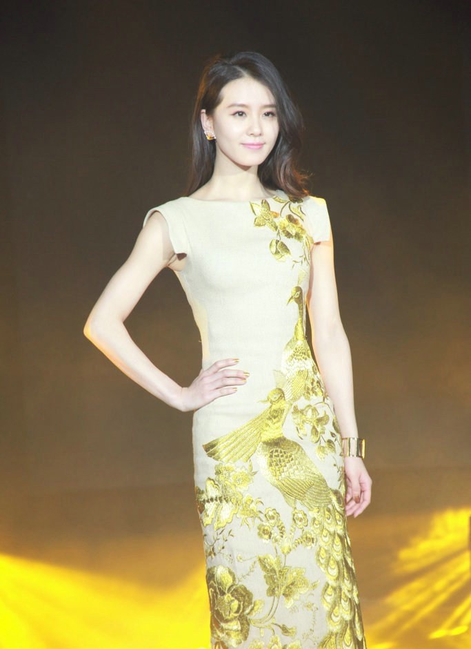 刘诗诗倚靠窗前，深色绣花旗袍衬托白皙肌肤，光影洒落肩头，她目光沉静望向远方，宛如一幅时光深处的静谧画卷