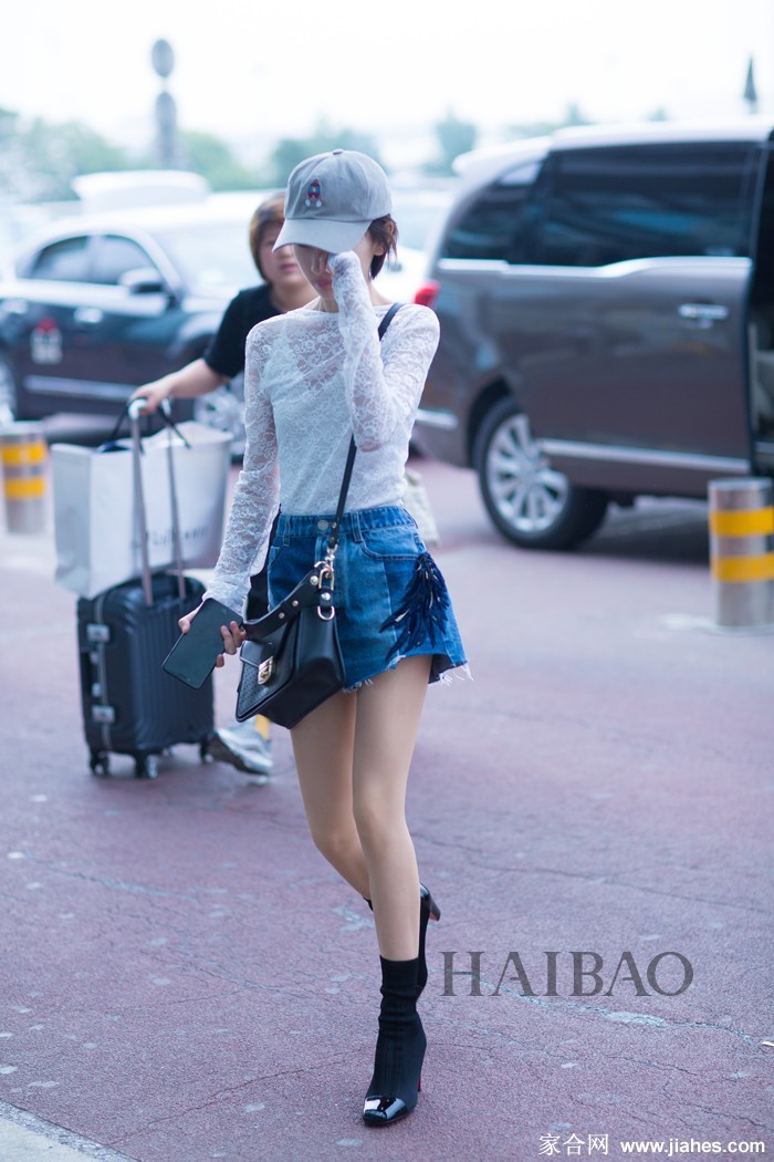 周冬雨举手向观众致意，裙摆随风微动，自信姿态气场全开