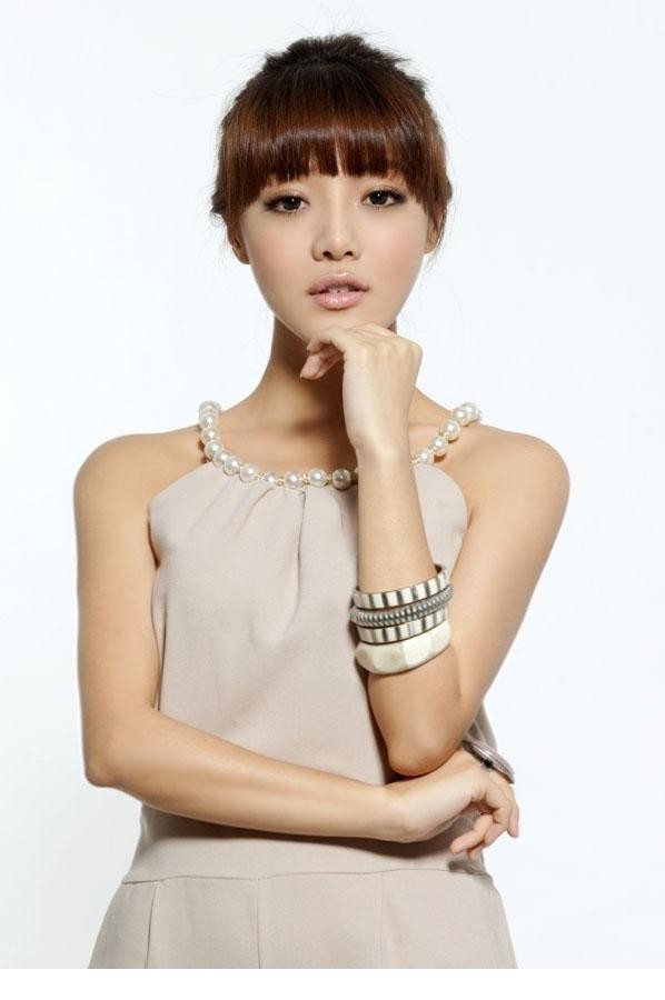 邓家佳身着裸色系服装倚靠光影处，回眸间眼神温柔而深邃，轻熟韵味悄然流淌