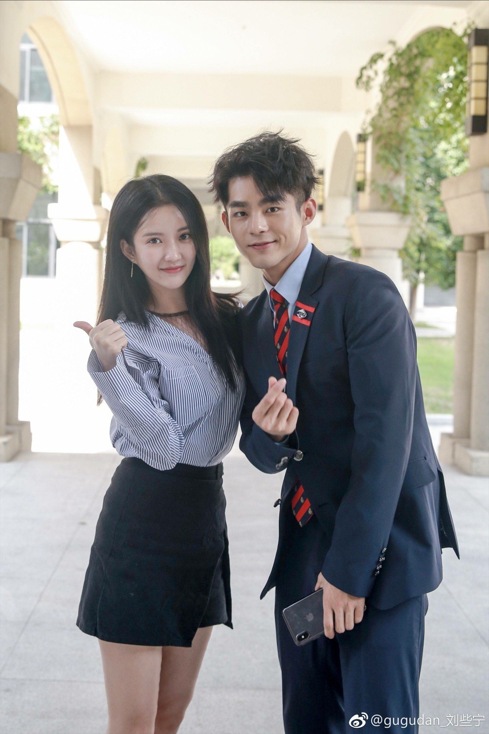 刘些宁坐在高脚凳上，双腿交叠展现长靴线条，背景的暖光营造出静谧而高级的氛围