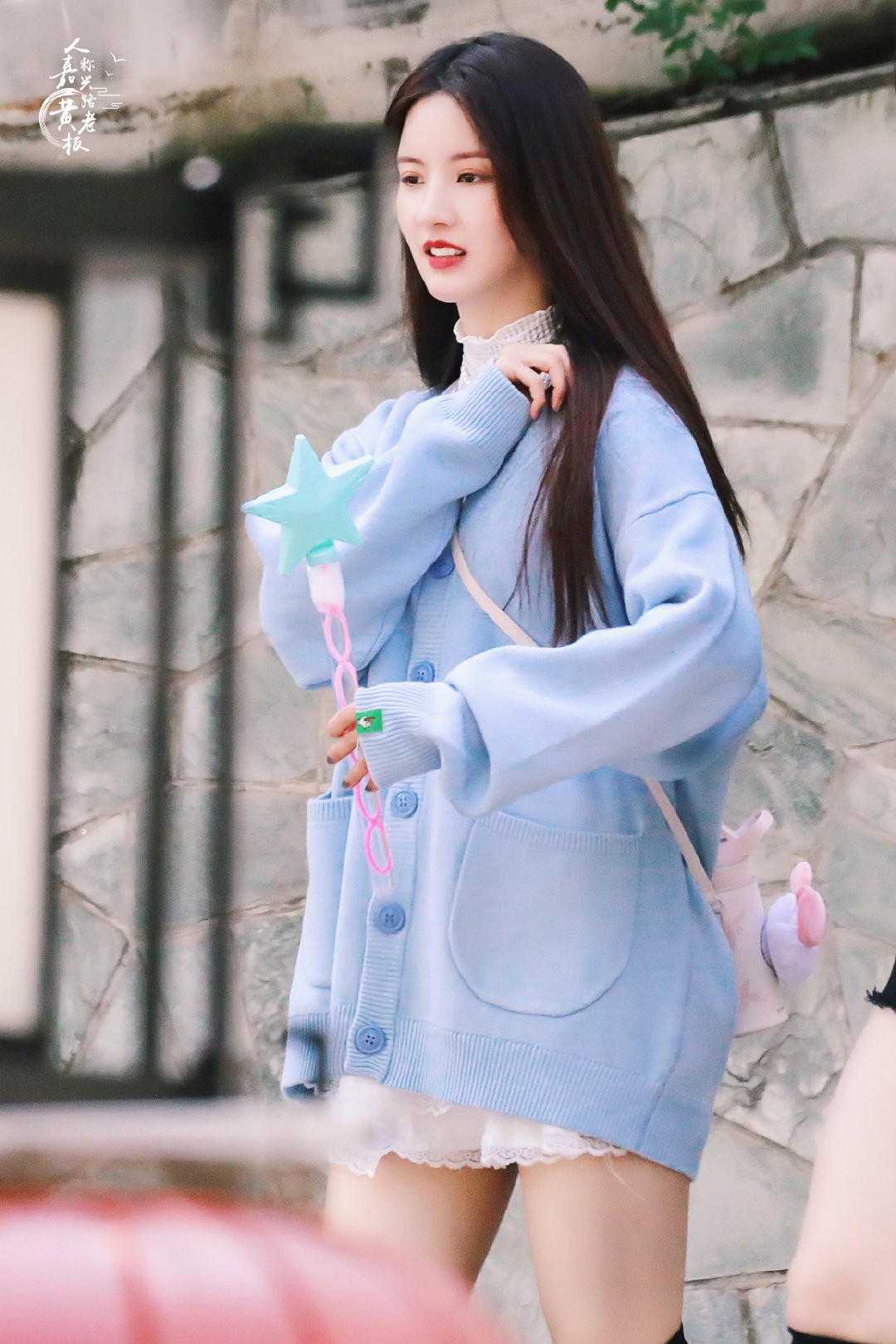 刘些宁穿长靴立于街角，身后是复古砖墙，她回眸间尽显冷艳与神秘气质