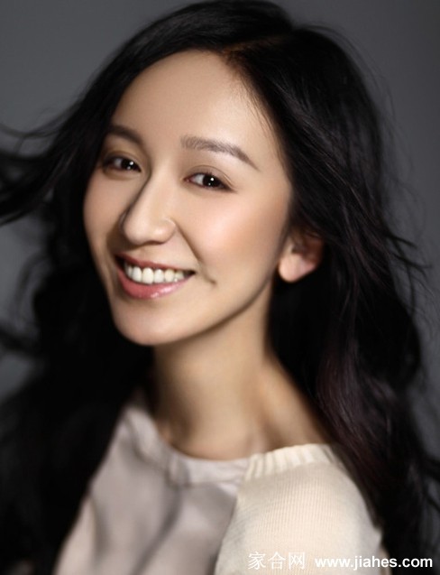 娄艺潇慵懒倚靠浅咖色背景，身着简约深色上衣，嘴角微扬的笑意淡然通透，尽显从容气质